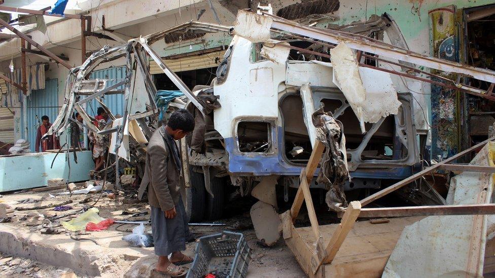 A man inspects a bus destroyed in a Saudi-led coalition air strike in Dahyan, Saada province, Yemen (10 August 2018)