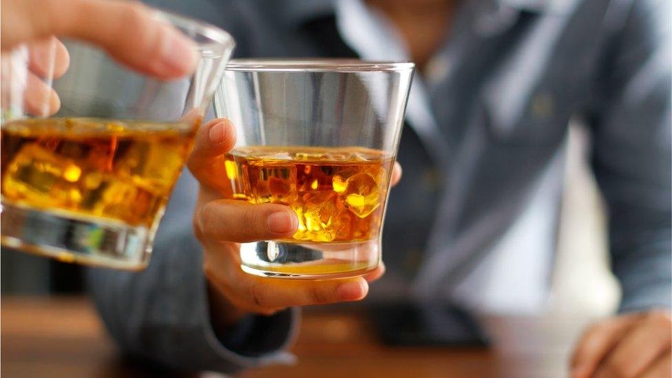 Two people holding whisky glasses