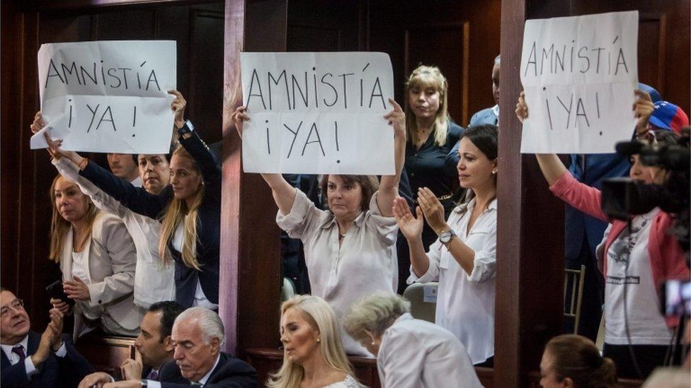 Opposition leaders and wives of imprisoned leaders, Lilian Tintori (3M), Mitzi Capriles (c), Maria Corina Machado (2R) Patricia Ceballos (R) hold banners where it reads "Amnesty Now" during the National Assembly Installation