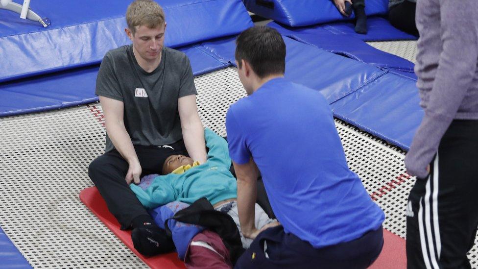 A couple of members of staff supporting a student lying on a trampoline