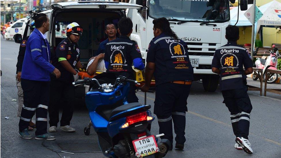 Thai rescue workers carry an injured man on a stretcher to an ambulance, in Hua Hin on 12 August 2016.