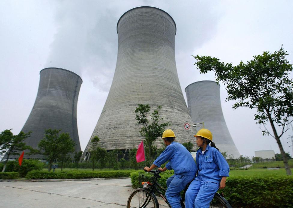 Workers cycle past Guangan power plants, 2004