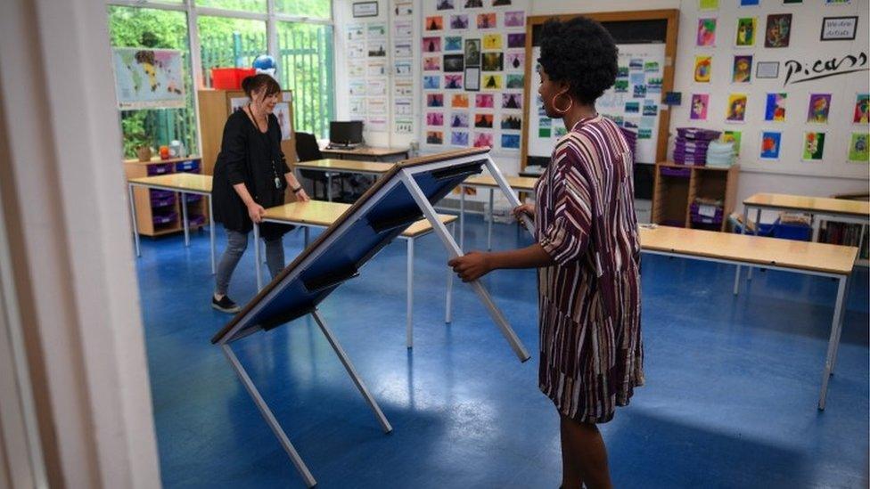 School staff rearrange the tables in a classroom ahead of the return of more students from Reception and Year Six of Muswell Hill Primary School on June 03, 2020 in London,