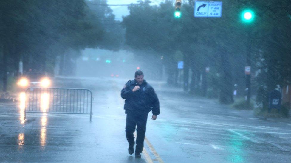 A police officer in Charleston is pelted with rain