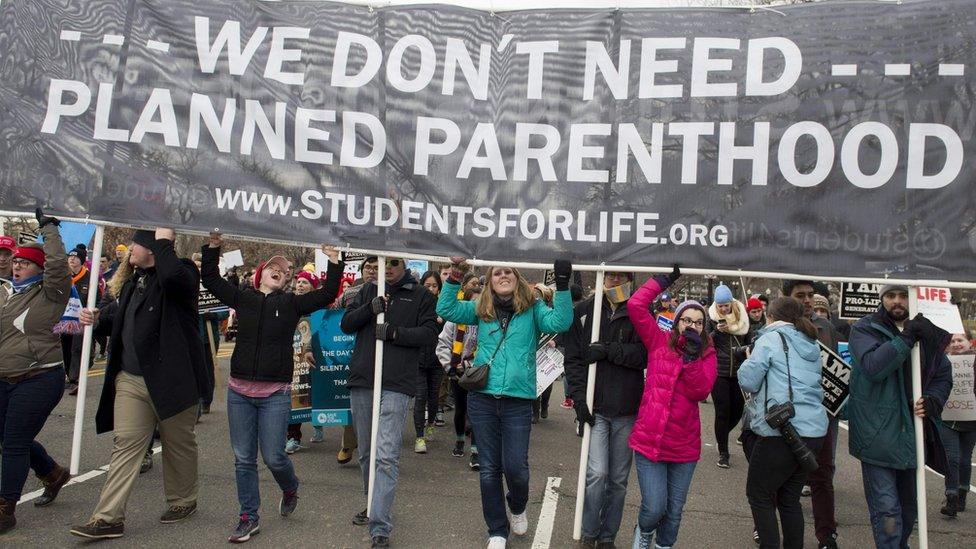 Young women hold a large banner reading "We don't need Planned Parenthood" aloft during the March for Life, 27 January