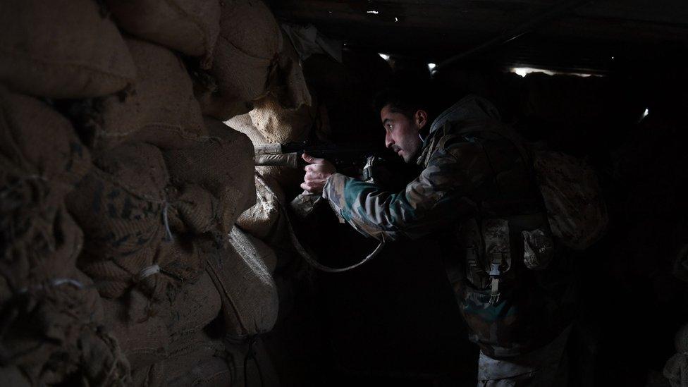 A member of Syrian government forces watches through the opening of a sandbag barricade in the southern countryside of the northern Kurdish-controlled city of Manbij on December 30, 2018