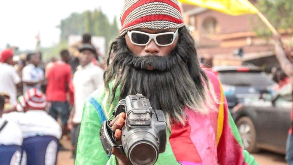 A man in a fake beard and video camera in Arondizuogu during the Ikeji Festival in Nigeria