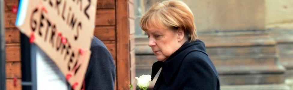 Angela Merkel brings a flower to the site of Monday's attack