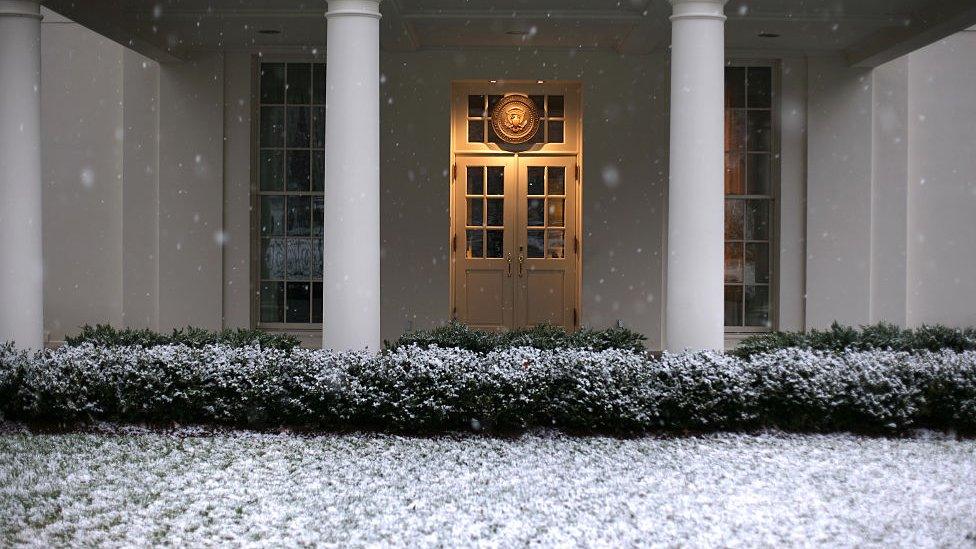 Snow falls in front of the entrance to the West Wing of the White House.