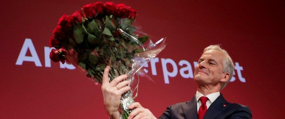 Jonas Gahr Stoere holds a bouquet of red roses