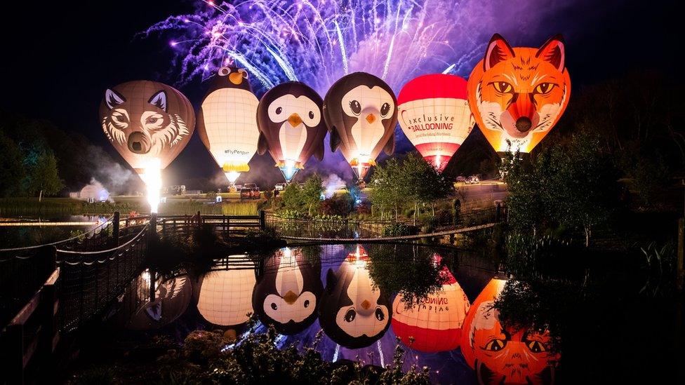 Tethered balloons light their burners during nightglow and firework displays