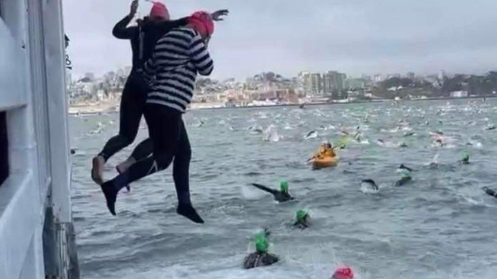 Sally Orange jumping from a boat to start her swim in convict clothes