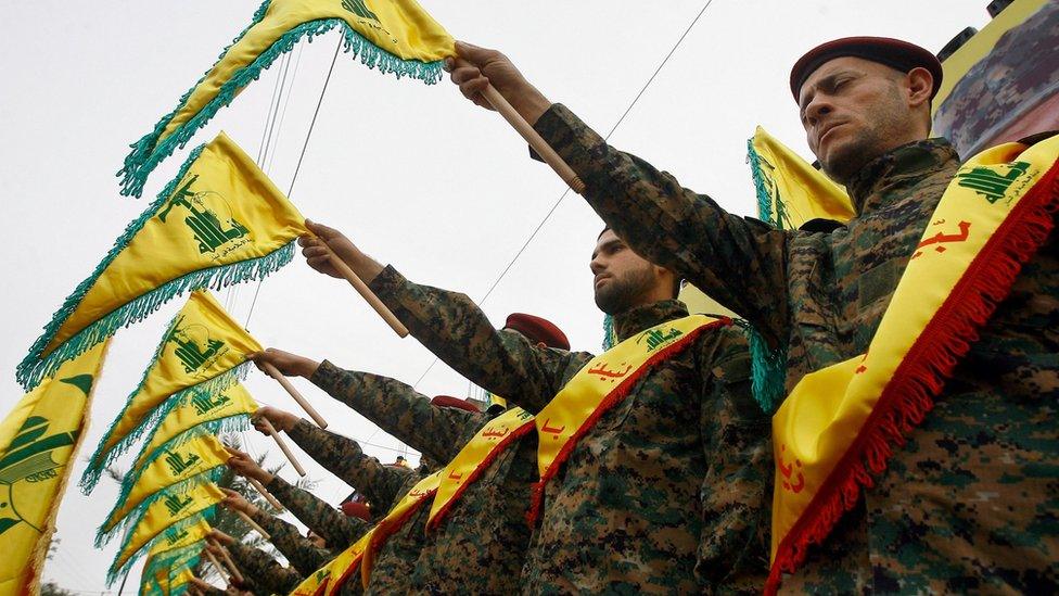 Hezbollah members hold up flags during a funeral for a Hezbollah fighters killed in Syria (2 March 2016)