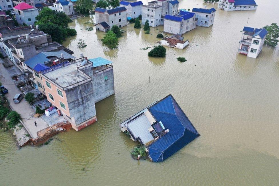 A building that has fallen over after flooding is seen partially submerged in floodwaters following heavy rainfall in the region, at a village near Poyang Lake, in Poyang county, Jiangxi province, China July 13, 2020