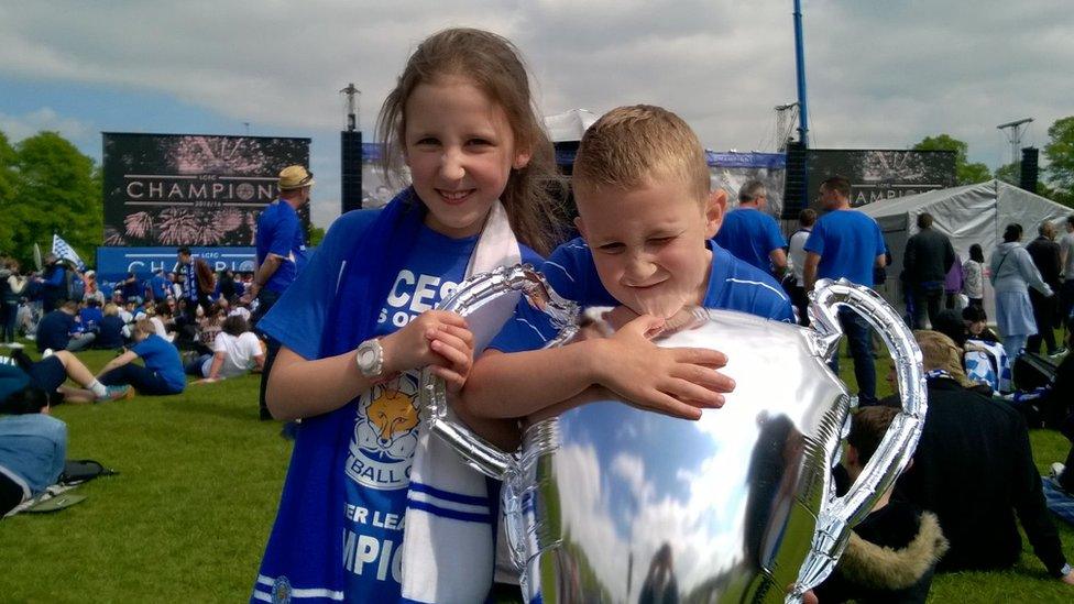 Two fans holding a balloon trophy