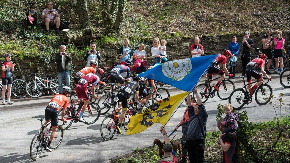 A man waving a Yorkshire flag watches the 2018 Tour de Yorkshire