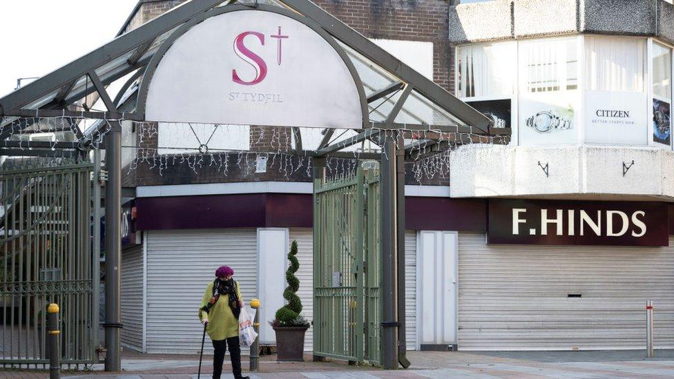 A woman wearing a face mask walks through a quiet Merthyr Tydfil town centre