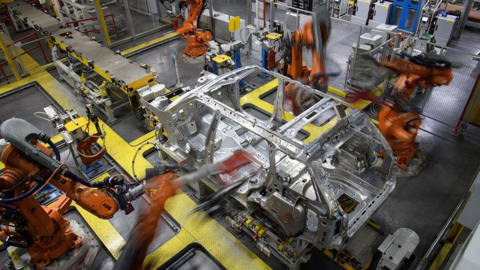 Robotic systems work on the chassis of a car during an automated stage of production at the Jaguar Land Rover factory