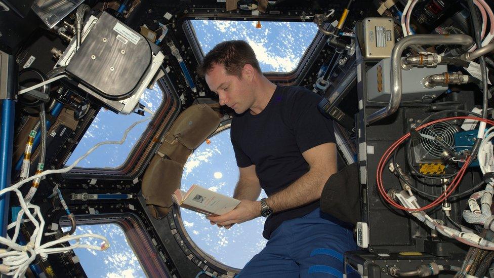 Thomas Pesquet reading a book on board the ISS