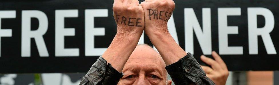 A man with the words "free press" written on the backs of his hands protests at EU headquarters in Brussels on 25 July 2017