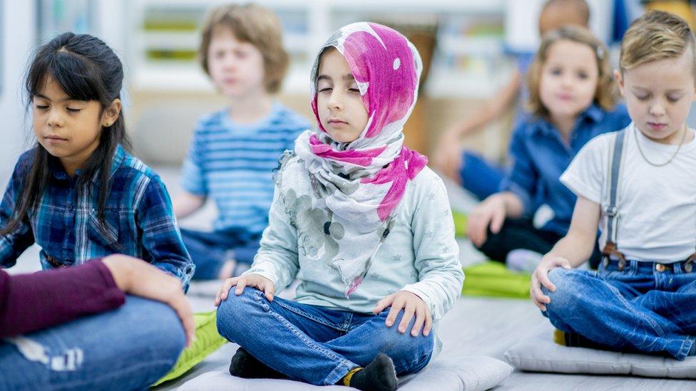 Kids sitting on floor with eyes closed