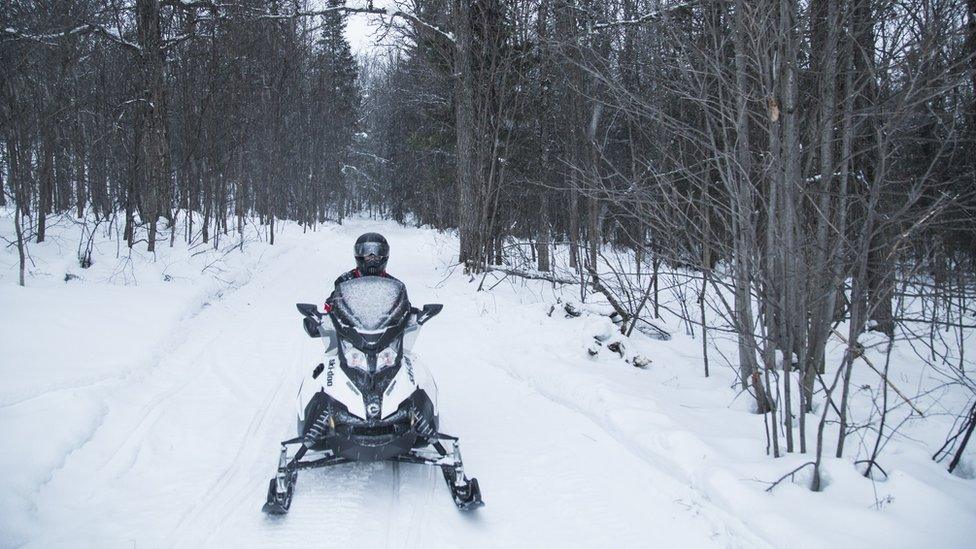 A woman riding a snowmobile