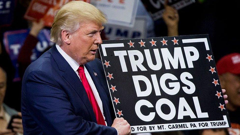 Donald Trump holds a sign supporting coal during a rally