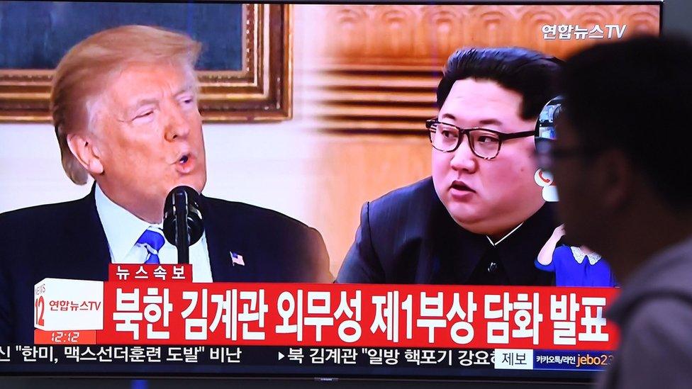 A man walks past a television news screen showing North Korean leader Kim Jong Un (R) and US President Donald Trump (L) at a railway station in Seoul on 16 May 2018