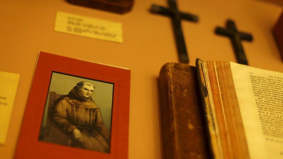 Wall with crosses and a picture of Serra