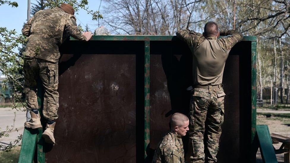 Young recruits undergo military training in the form of an obstacle course at the recruiting centre in Kyiv