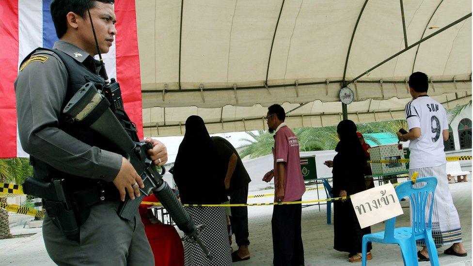 A Thai policeman stands guard during a vote on a new constitution