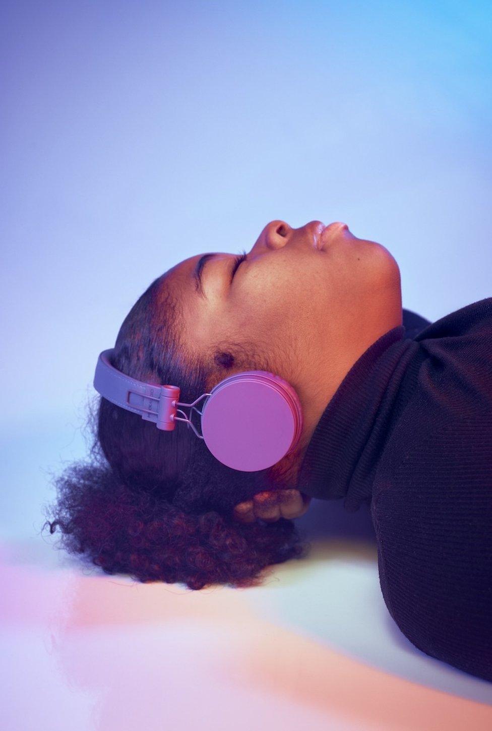 A portrait of a woman lying on the floor listening to headphones