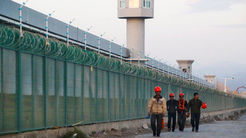 Workers walk by the perimeter fence of what is officially known as a vocational skills education centre in Dabancheng in Xinjiang Uighur Autonomous Region, China September 4, 2018.