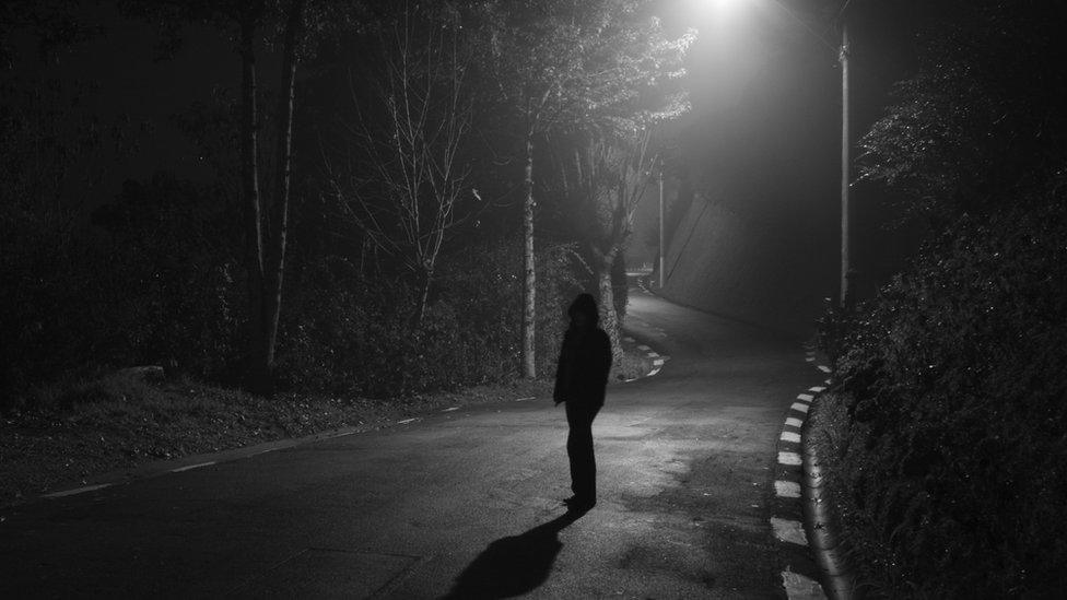 Person standing under a streetlight in shadow