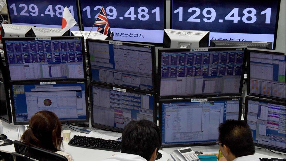 Traders check computer screens showing the Japanese yen rate against the British pound at a brokerage in Tokyo on October 7, 2016