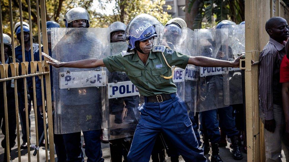 Zimbabwean anti riot police officers close the gate of the Rainbow Towers where the election's results were announced, as supporters of the opposition party Movement for Democratic Change (MDC) protest against alleged widespread fraud in Harare, 1 August 2018