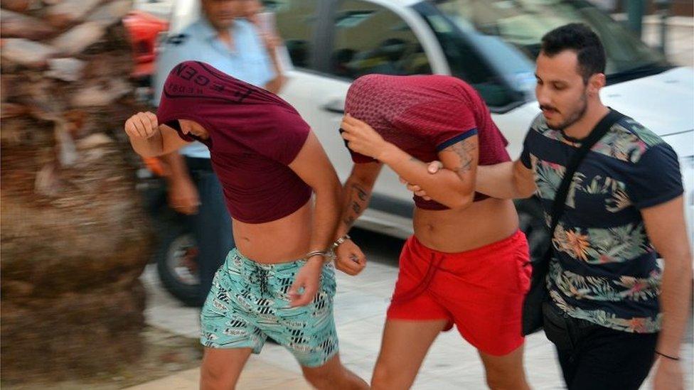 Suspects, with their heads covered, are escorted to the prosecutor's office by Greek police on the island of Zakyntho, Greece.