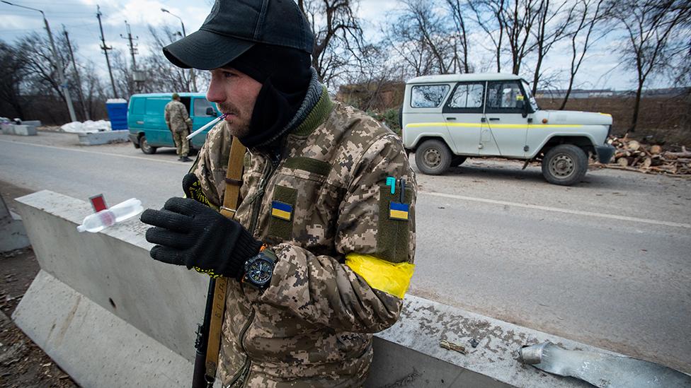 A soldiers smokes a cigarette amid sub-zero conditions as Ukraine Army troops dig in at frontline trench positions to continue repelling Russian attacks, east of the strategic port city of Mykolaiv, on March 10