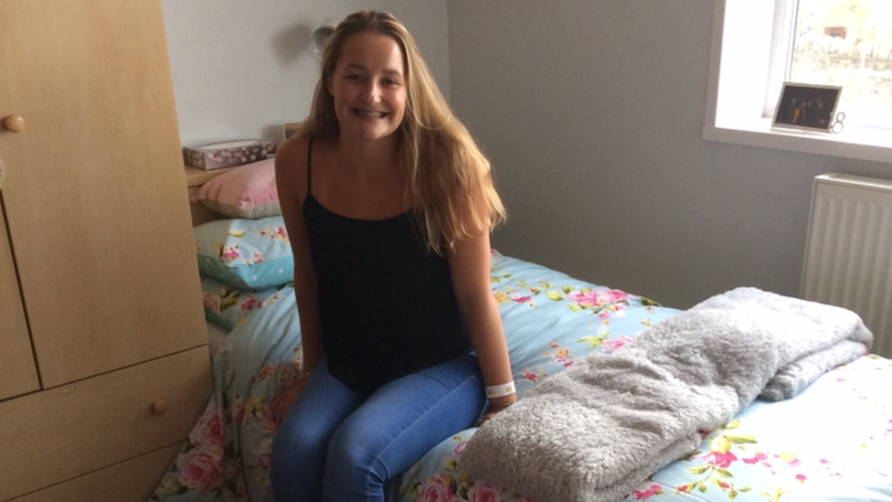 Imogen sitting on a bed in her university room just after moving into halls