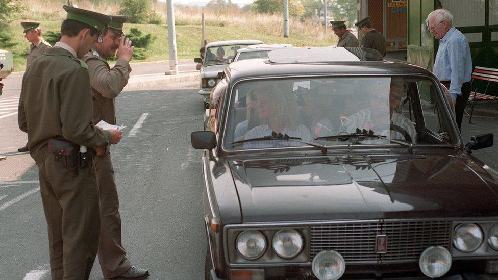 A Hungarian customs officer checks the passports of East Germans on the Hungarian side of the Austrian-Hungarian border in 1989