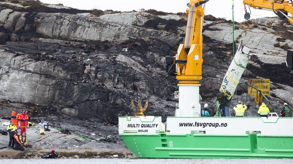 A vessel lifts up part of the crashed helicopter