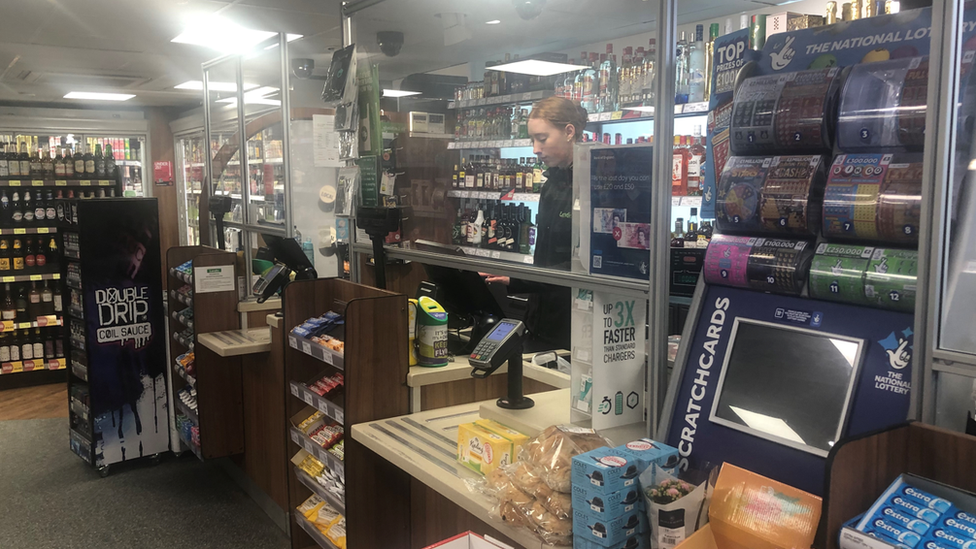 A worker at the till of Ben Simons' shop