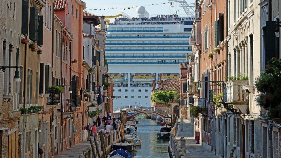 A large cruise ship visible at the end of a narrow canal in Venice