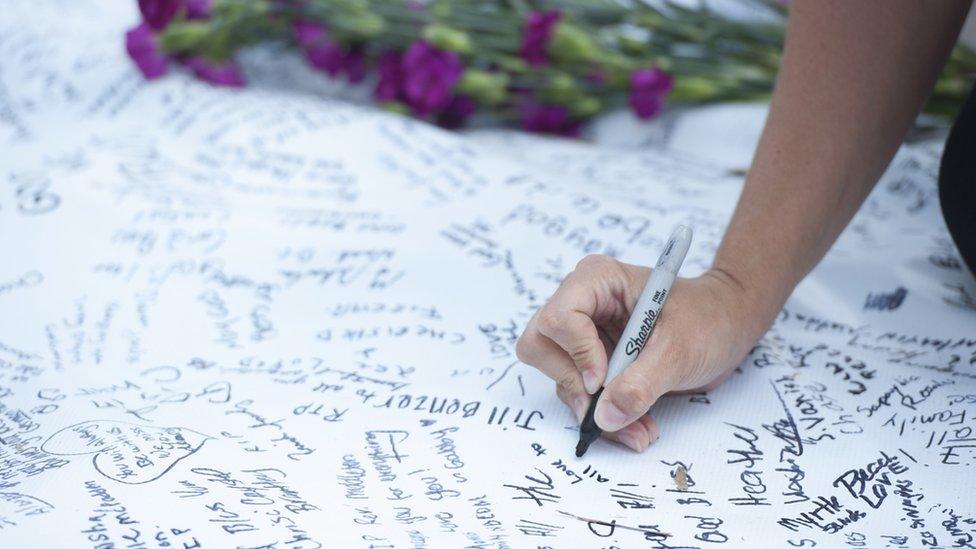 2015-06-20. Members of the public signed a large condolence sheet in front of Emanuel AME Church on Saturday evening, where nine churchgoers were murdered three days earlier. Colm O'Molloy for BBC News.