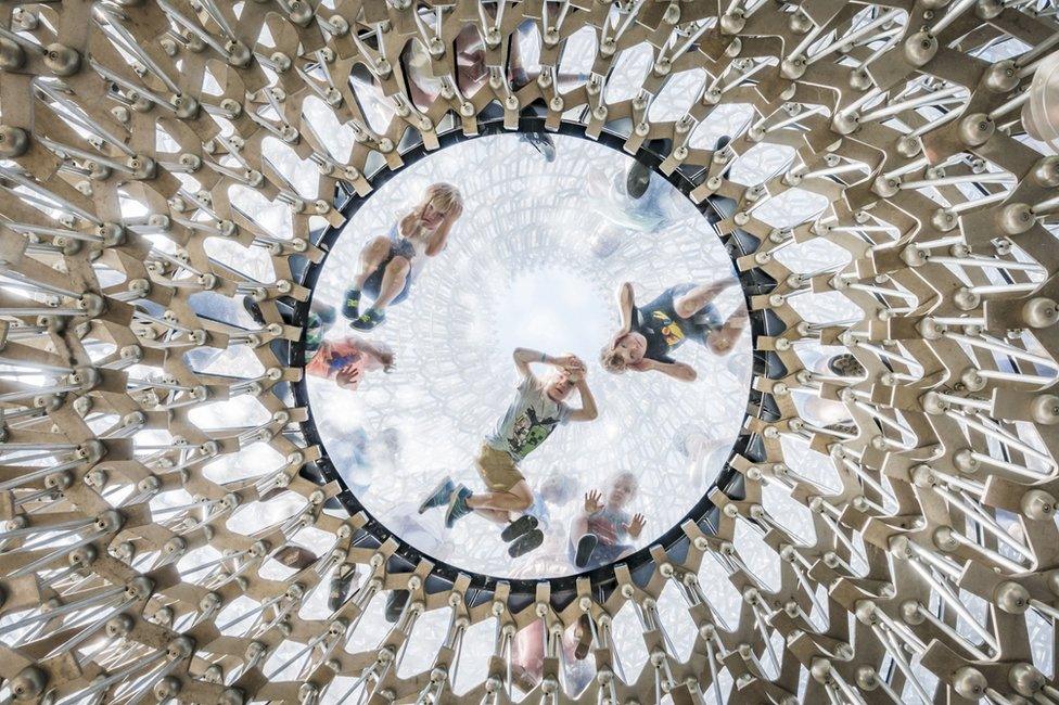 Children looking down through a glass-domed ceiling