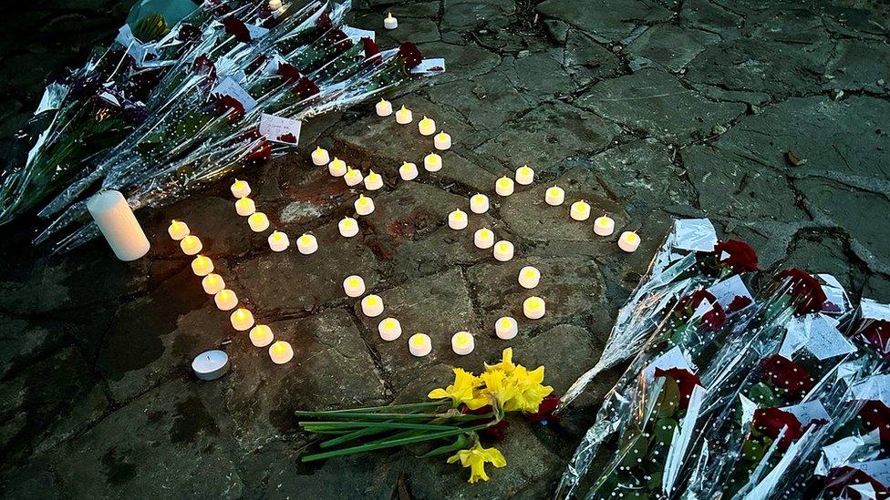 Candles and flowers laid out on the ground