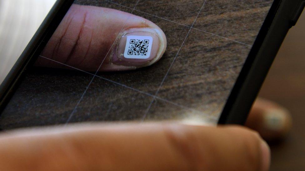 An Iruma city official scans the QR code displayed on a fingernail using a smartphone, 5 December 2016