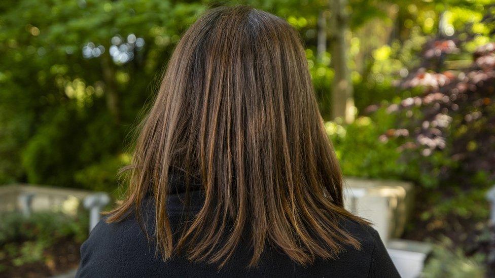 A brunette woman facing away from the camera