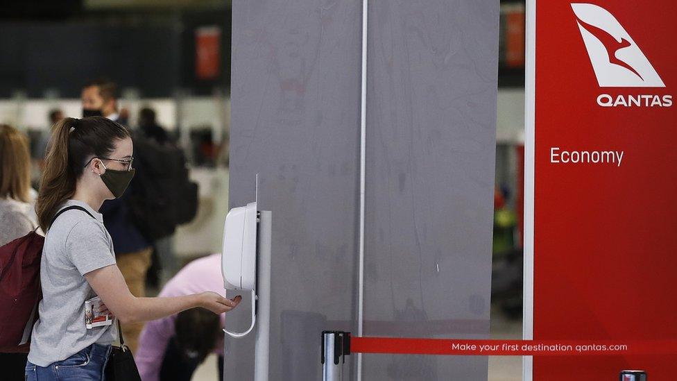 People sanitise their hands at Melbourne Airport after checking in for flights to New South Wales, 23 November 2020