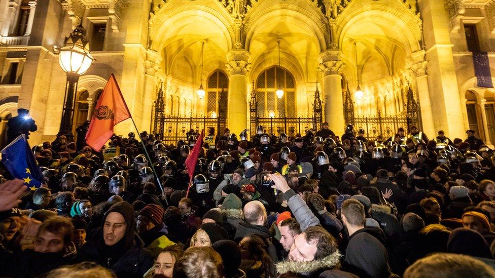 A large crowd presses against the line of riot police in front of the parliament building in Budapest